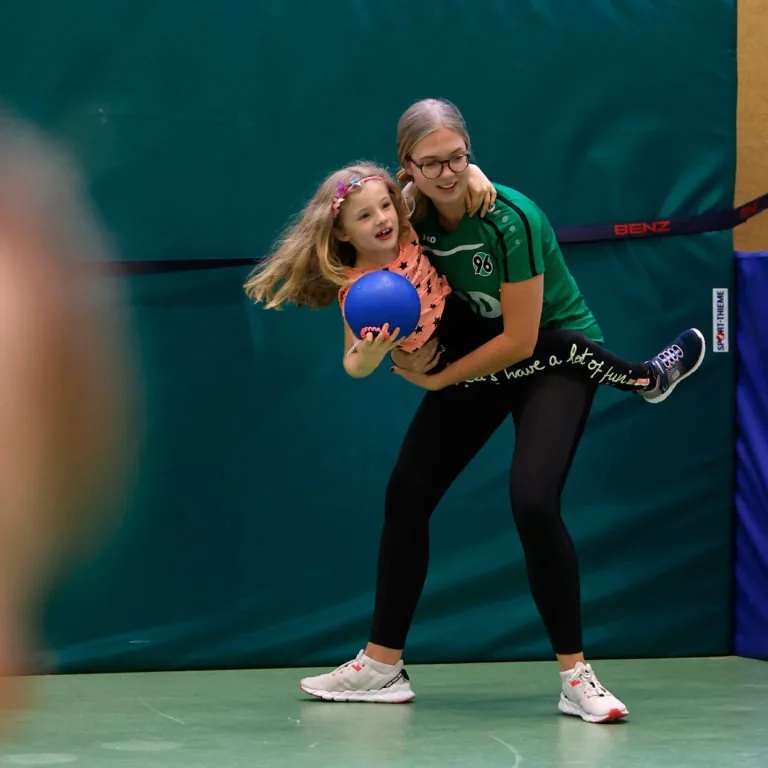 Kindersport bei Hannover 96: Trainerin mit Mädchen und Handball in der Halle